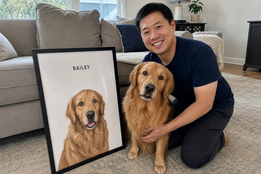 A man kneeling beside his golden retriever and her framed portrait, propped against the sofa.